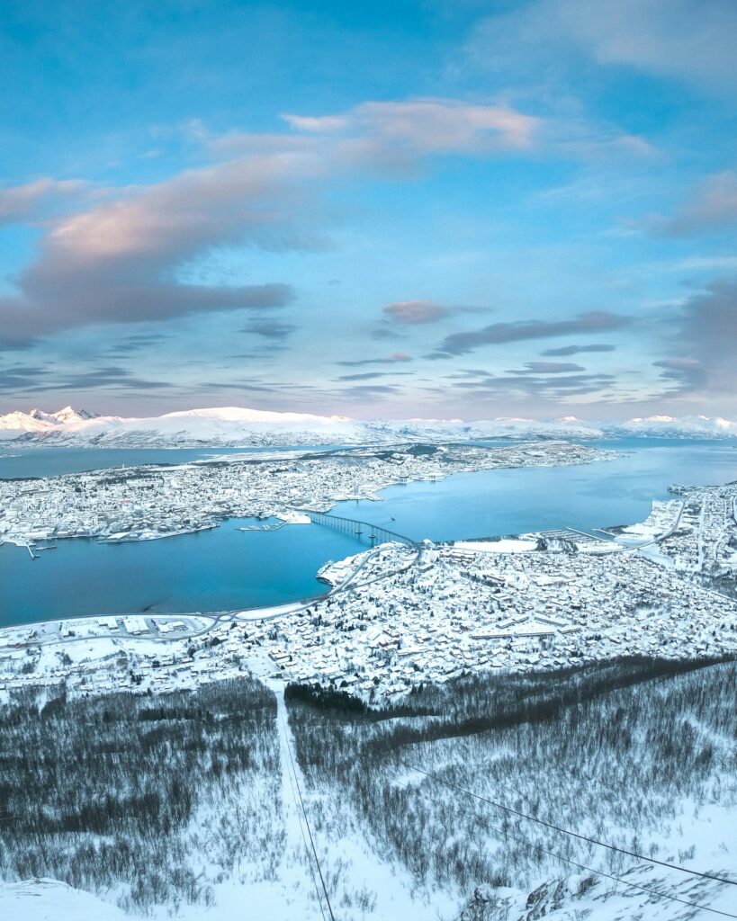 Breathtaking aerial view of a snow-covered town by a serene river in the wintertime.