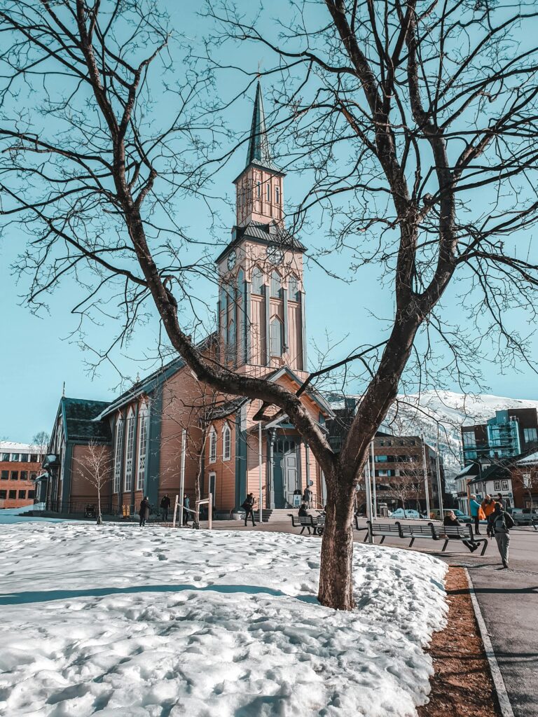 A picturesque church surrounded by snow in a quaint winter town setting.