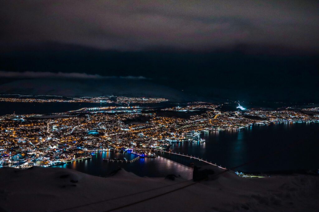 Breathtaking aerial night view of Tromsø, showcasing city lights and serene waters.