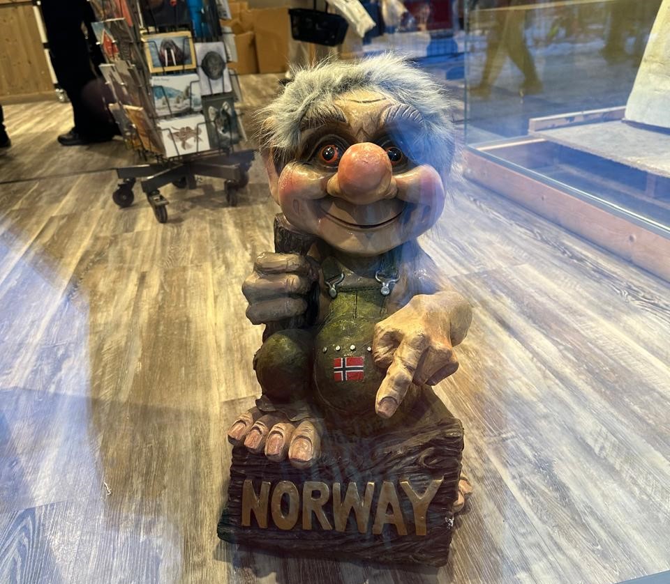 Escultura de um troll em frente a uma loja de souvenirs em Tromsø, Noruega, representando a tradição e o folclore nórdico na cultura local.